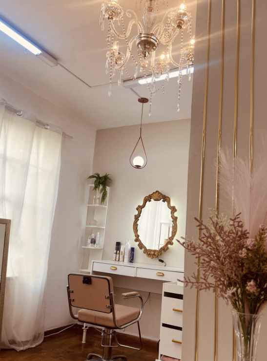 Ambiente elegante do Studio Michele Copertino com penteadeira, lustre e detalhes dourados